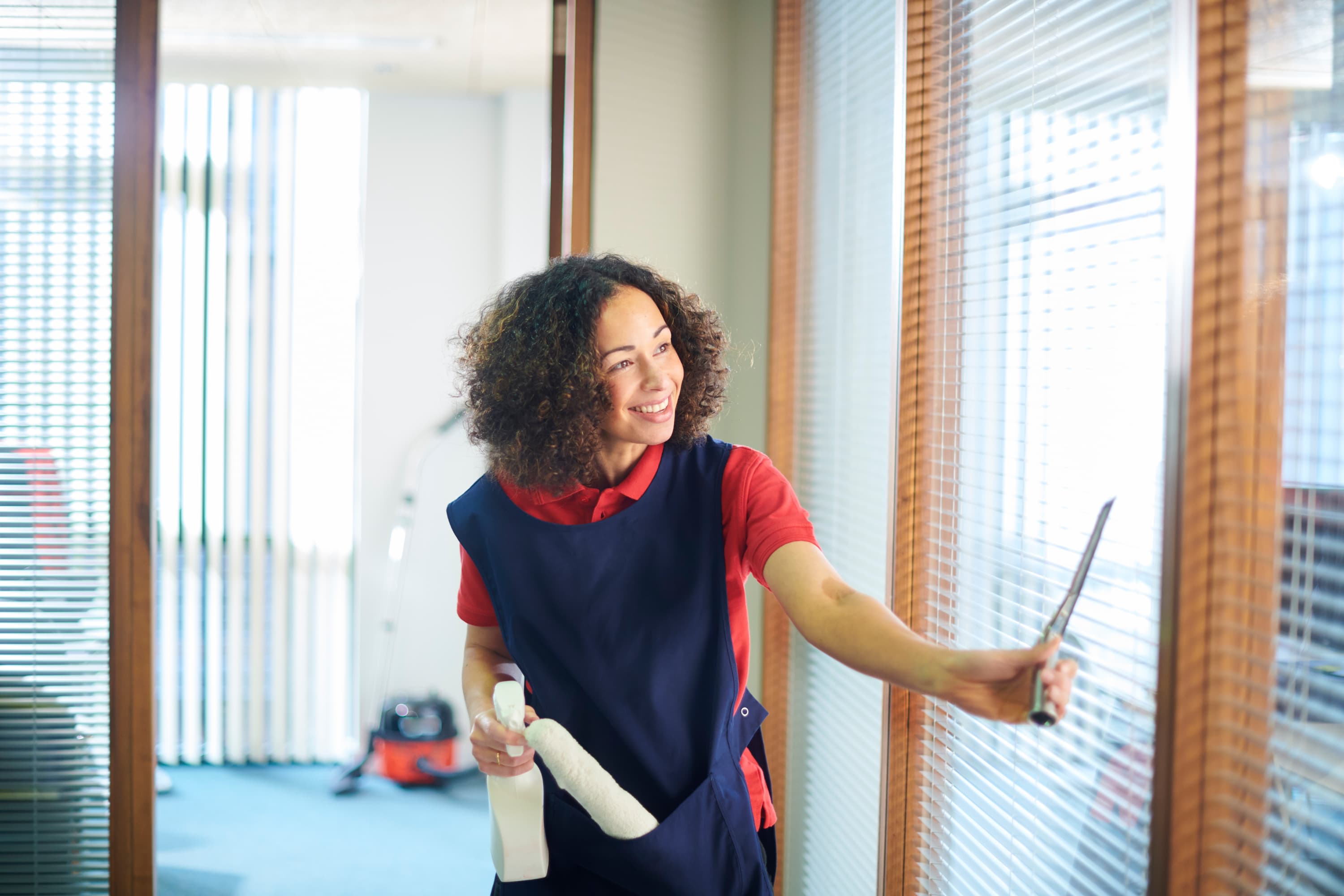 Professional cleaner using a squeegee on office windows
