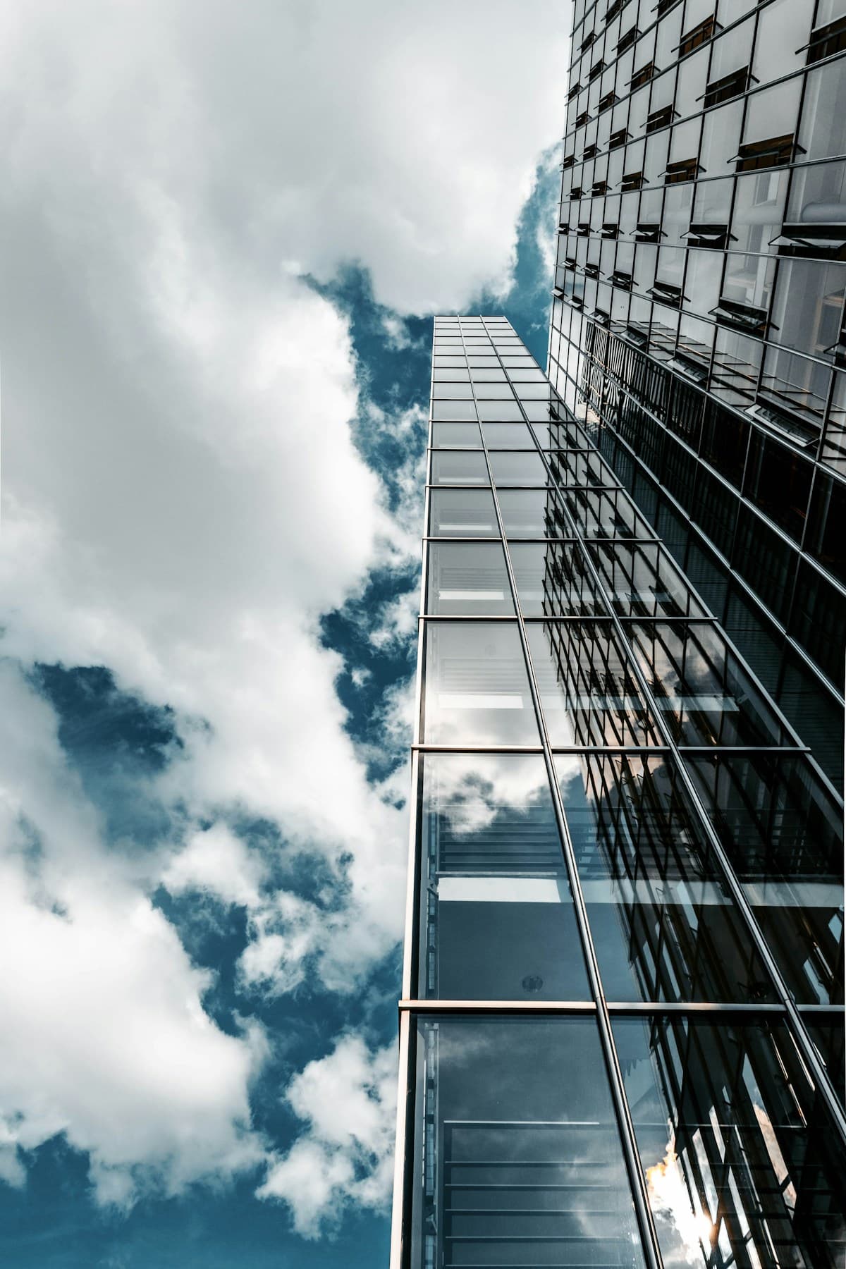 Glass-fronted commercial building with gleaming windows reflecting clouds