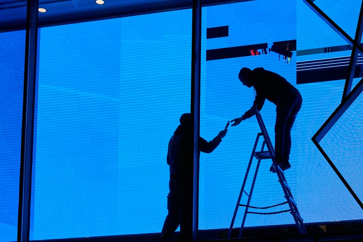 Workers cleaning tall glass panels at height